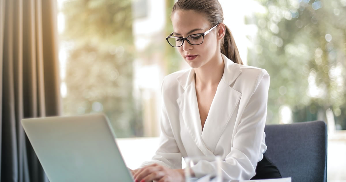 female entrepreneur writing on laptop at desk