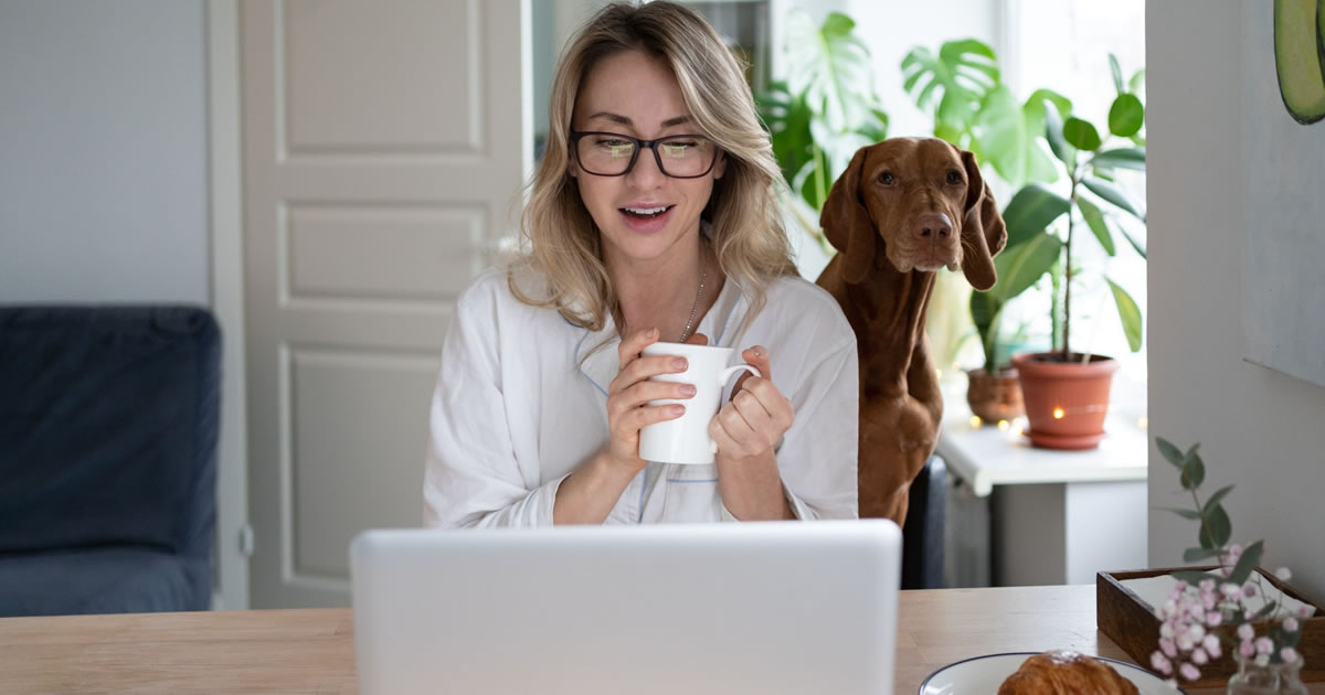 Woman writer sitting in front of a laptop with her dog