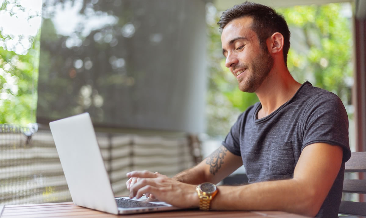 smiling man writing on laptop at desk