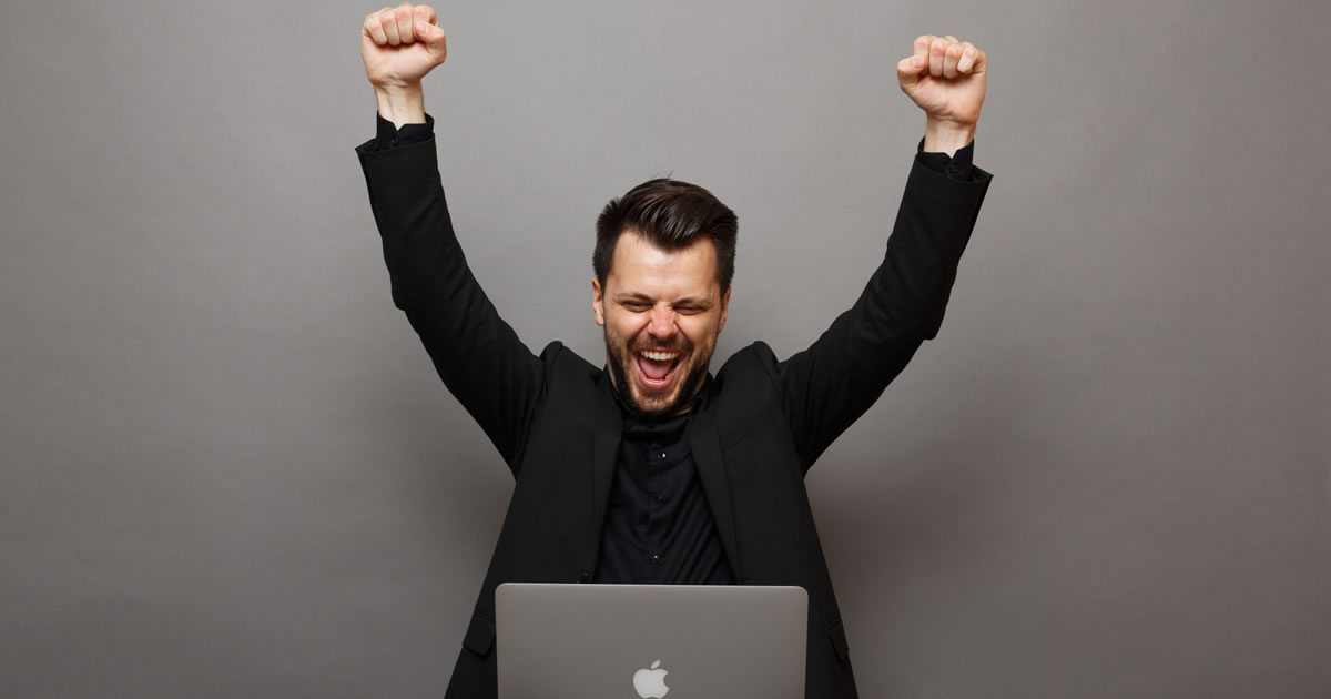 Happy writer with laptop and hands in the air in victory
