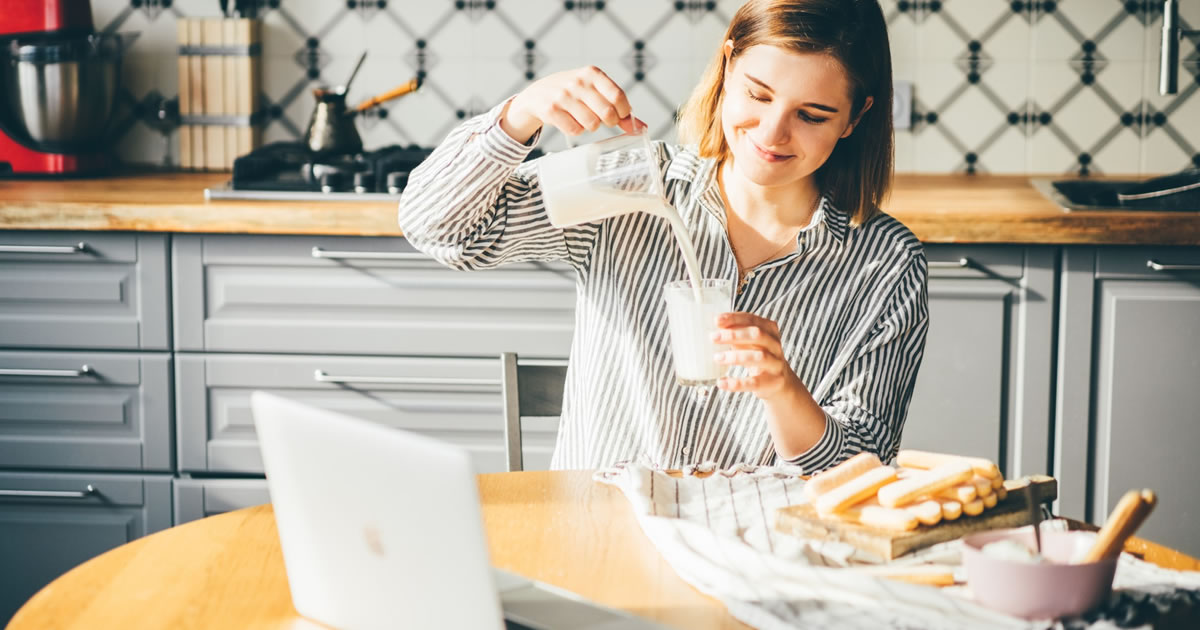 woman measuring ingredients in kitchen with laptop