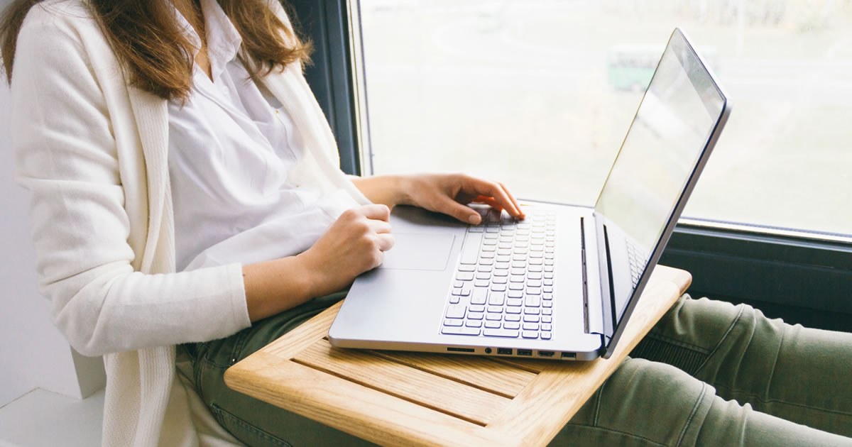 Woman writing blog on laptop computer