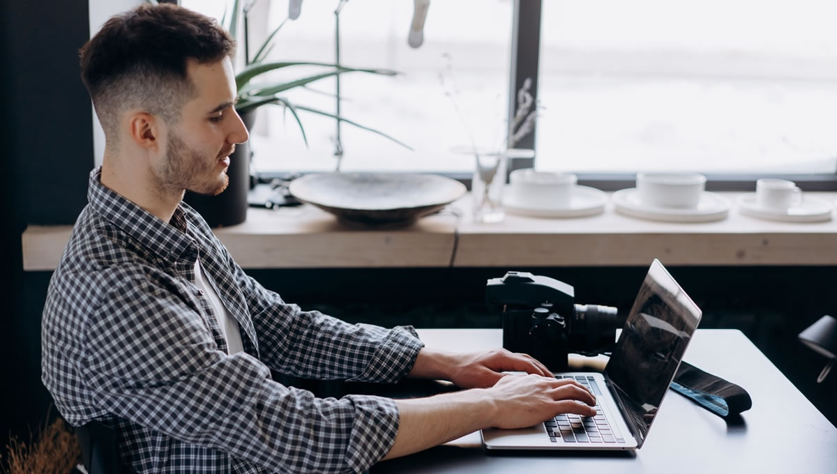 Homem escrevendo no laptop em uma mesa