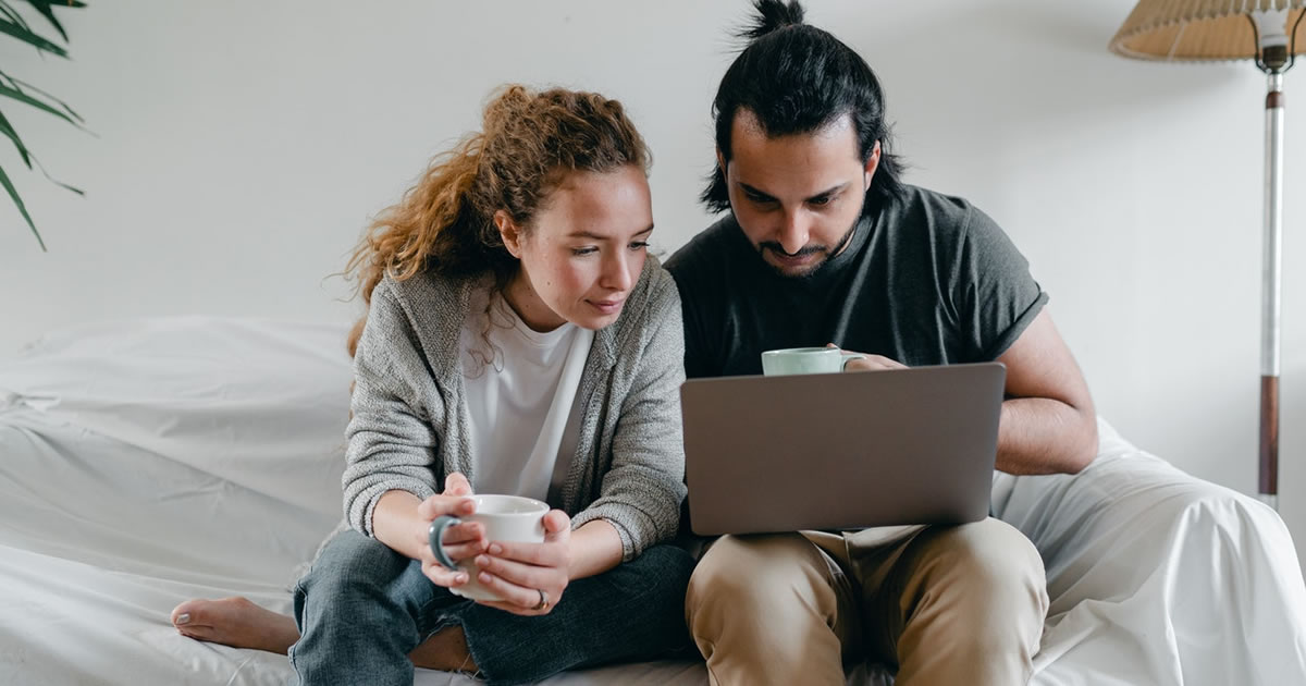 couple on sofa concentrating on laptop screen