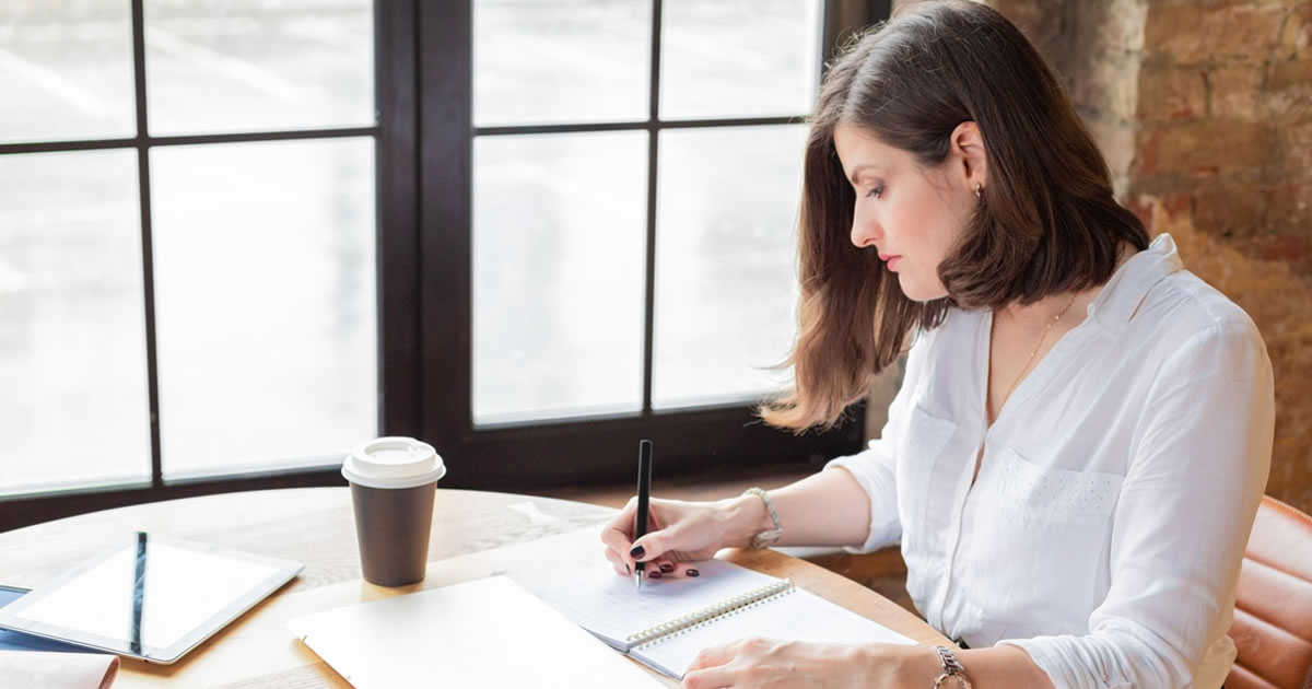 Businesswoman writing in a notebook at a table