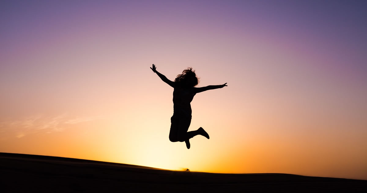 silhouette photo of person jumping against sunset background