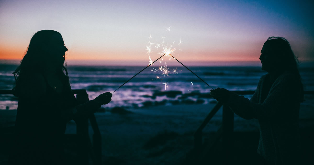 friends with sparklers on beach celebrating success