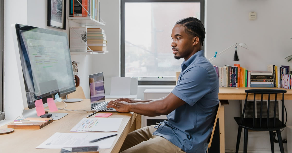 Male freelance writer working at desk with computers