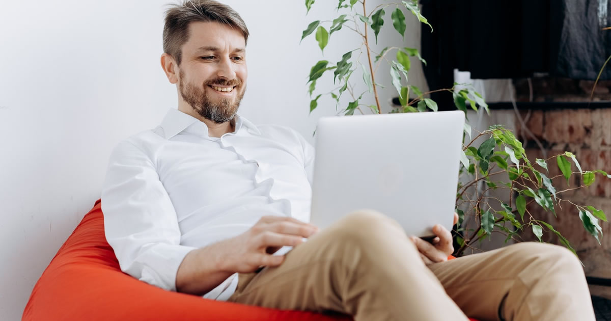 Happy male freelancer writing on his laptop