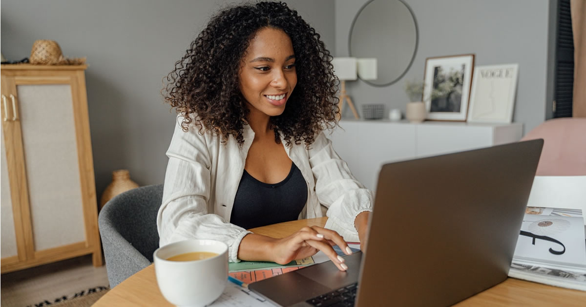 Mulher freelancer escrevendo em um laptop em uma mesa de madeira