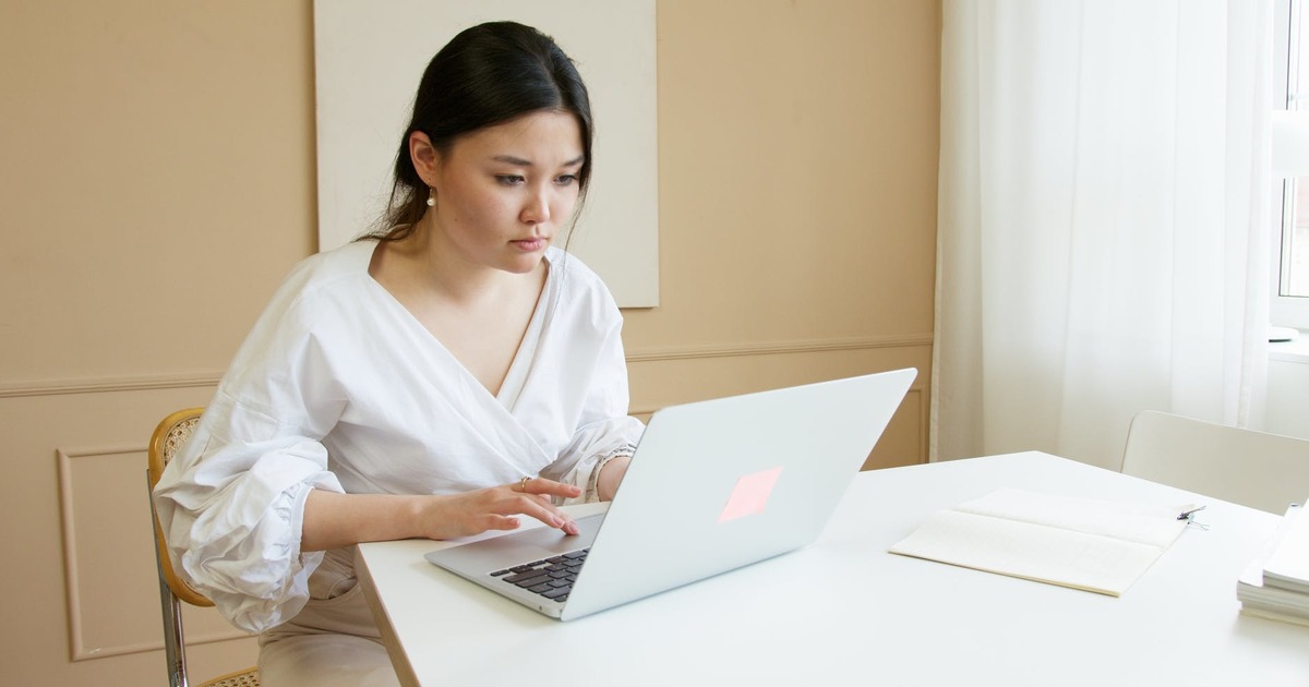 Woman sitting at desk looking at screen of laptop computer