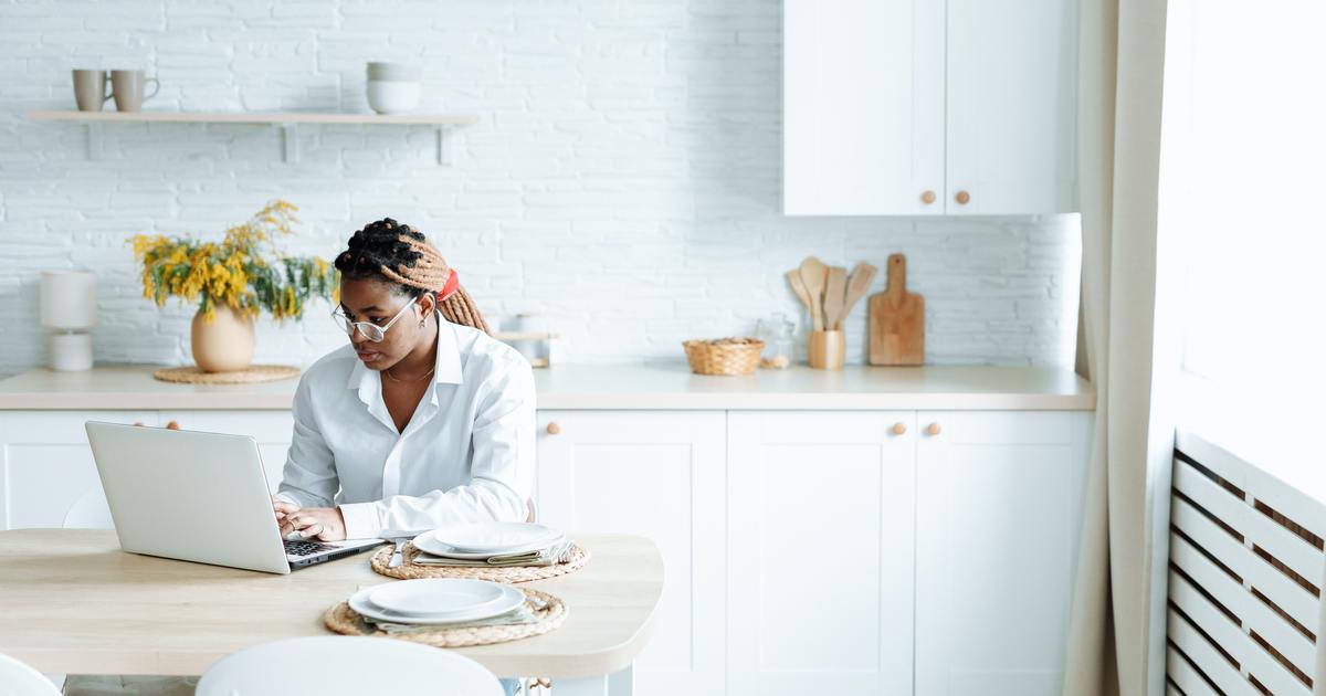 Mulher digitando em um laptop na cozinha