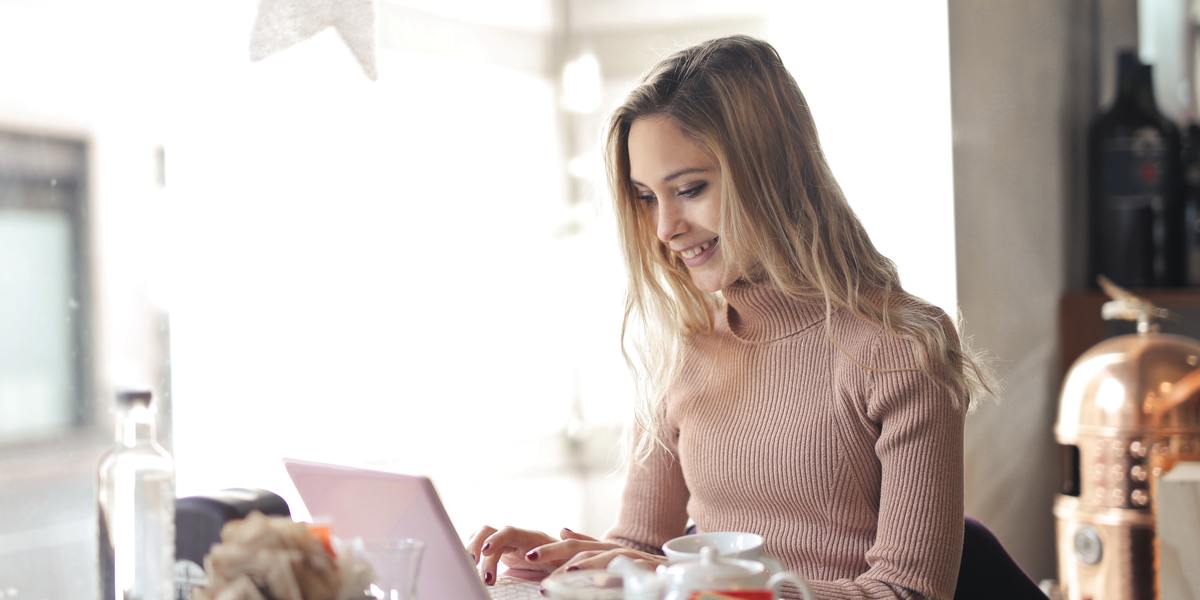 Happy woman writing on laptop