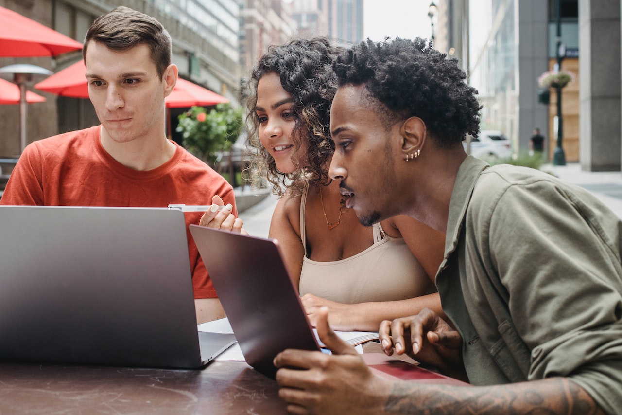 Happy young diverse friends looking on social media on laptops