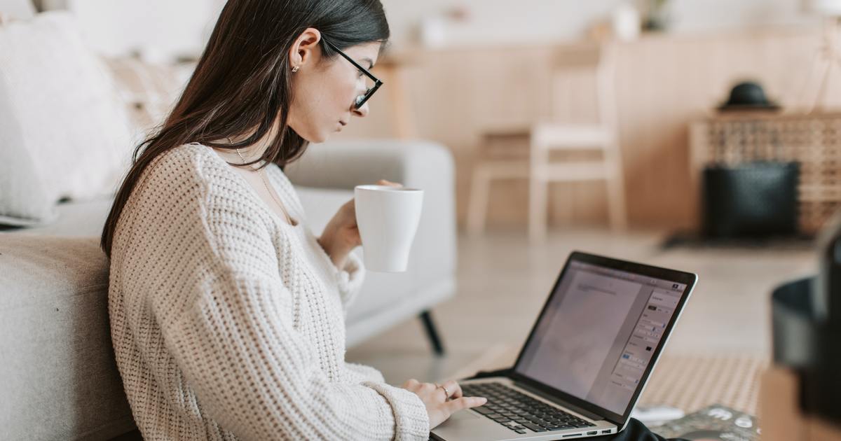 Woman typing on laptop while drinking coffee