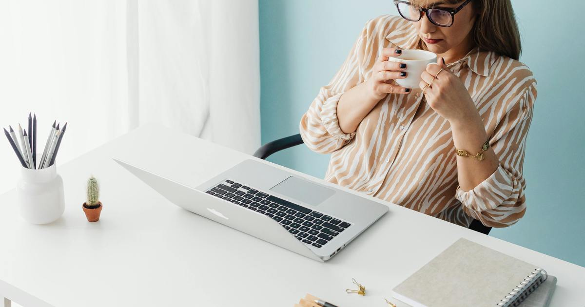 Writer drinking coffee while looking at laptop