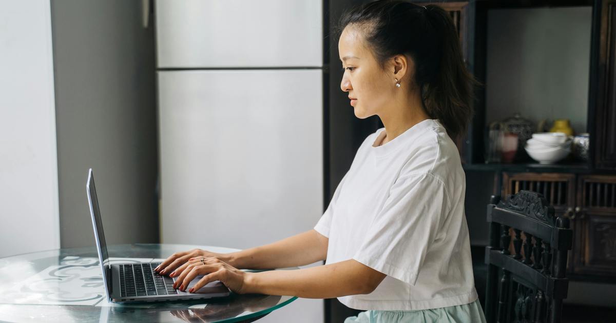 Woman sitting at a table typing on a laptop computer