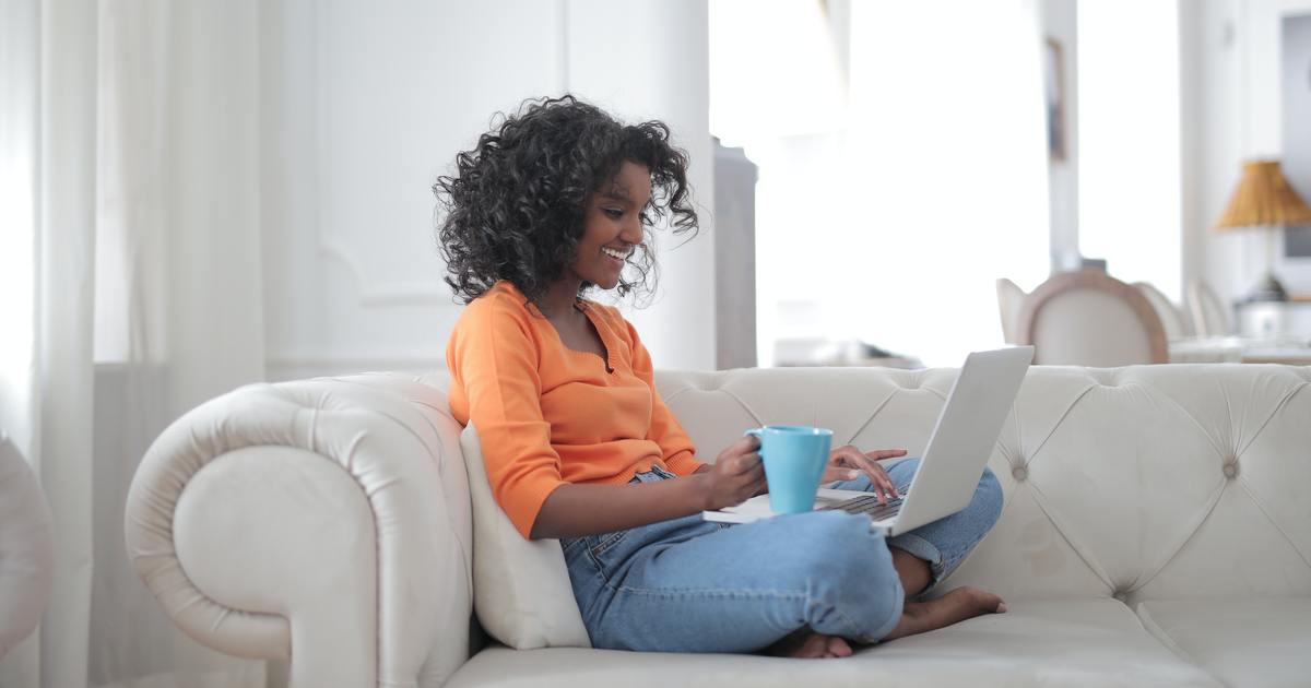 Escritor sentado no sofá com laptop e caneca de café