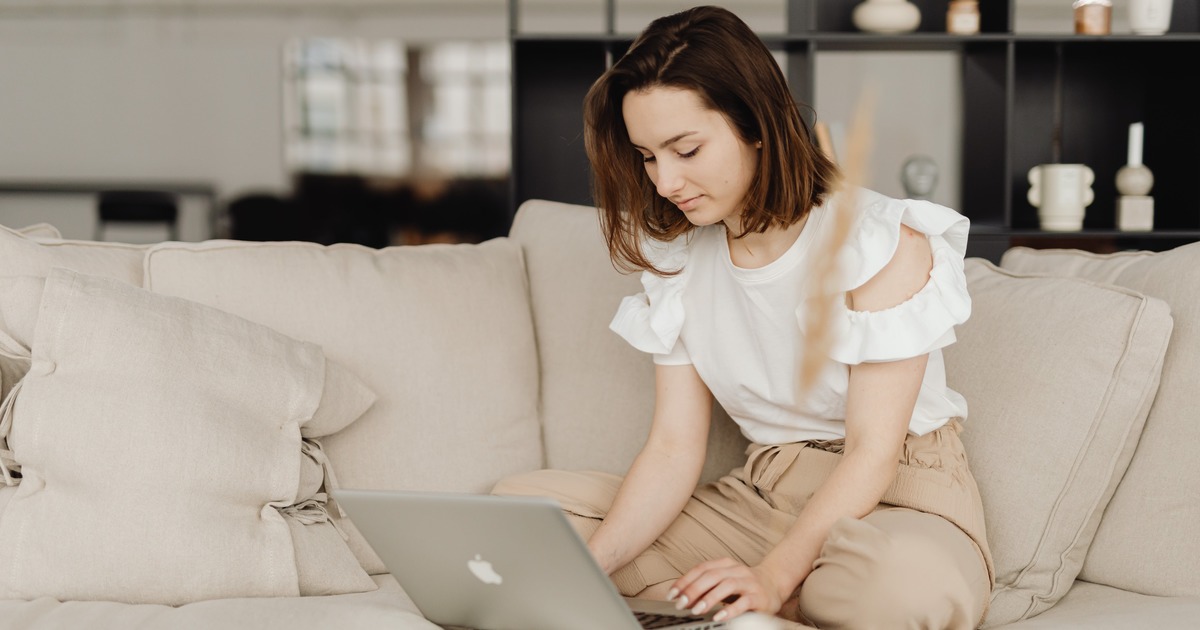 Writer sitting on a couch typing on a laptop