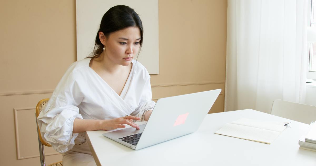 Writer sitting at a table typing on laptop