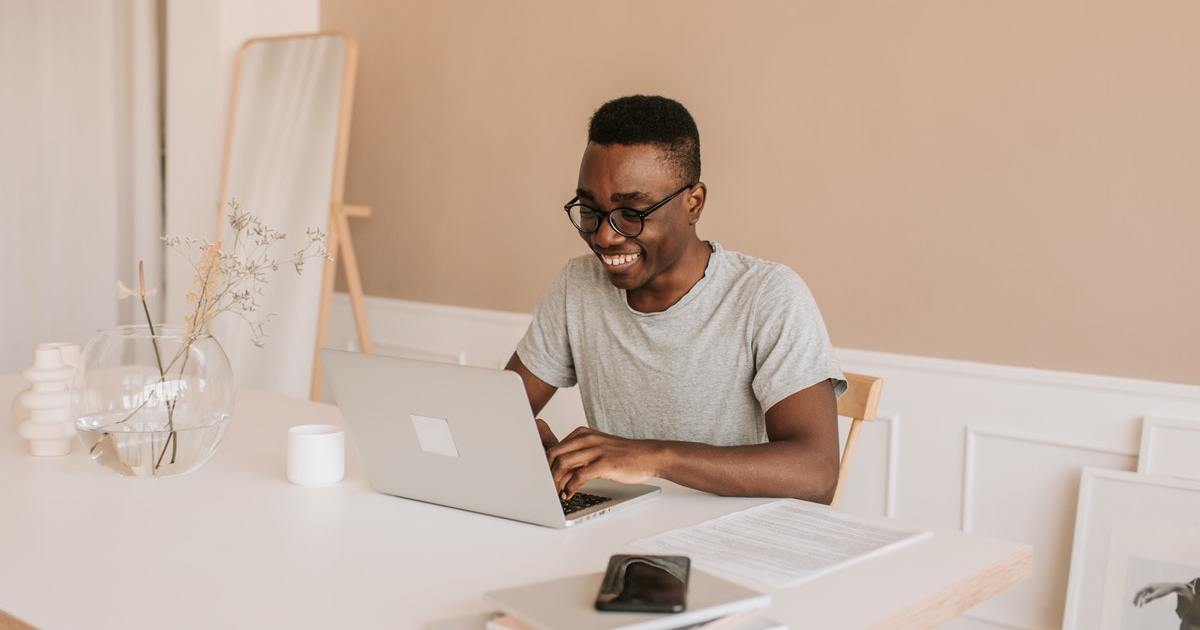 Smiling person sitting at desk typing on laptop computer