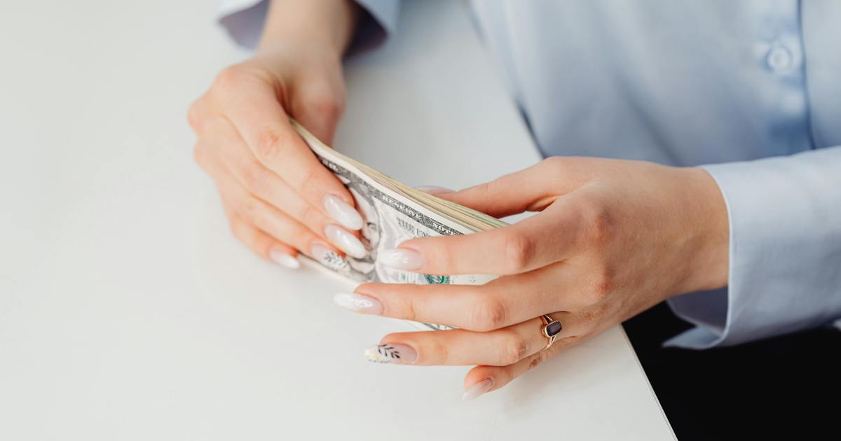 Close-up of hands holding a stack of money