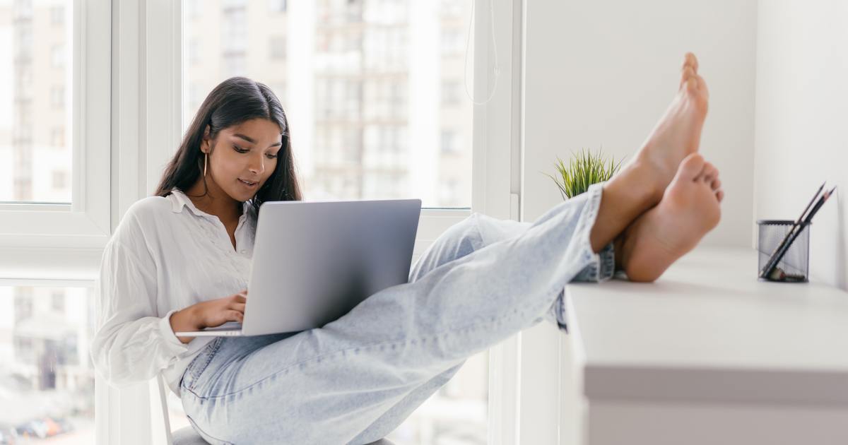 Escritor digitando no laptop com os pés sobre a mesa