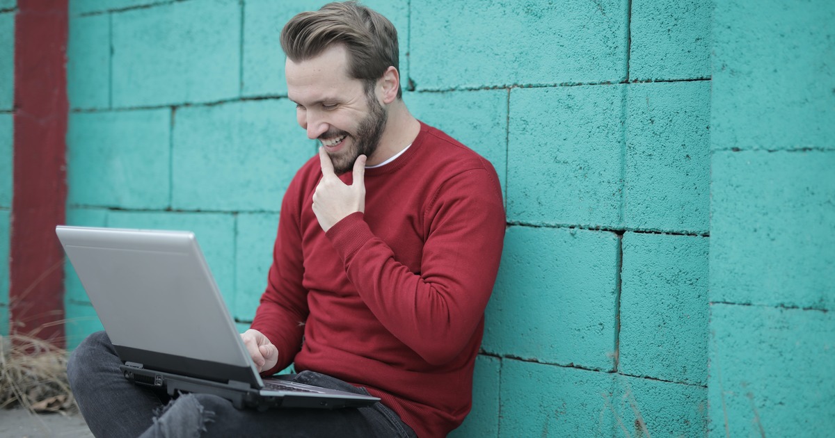 Escritor sentado do lado de fora com laptop