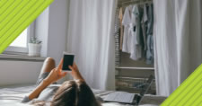 Person on their bed using mobile phone next to laptop