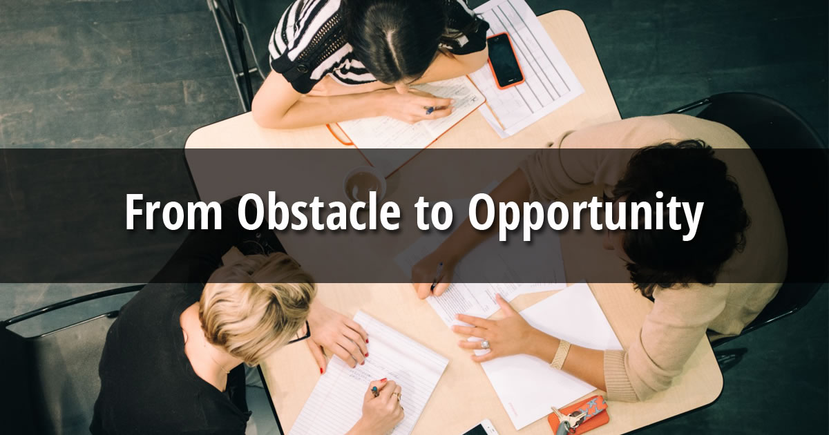 Overhead photo of three businesswomen sitting at a table with papers, notepads, and pens with text overlay From Obstacle to Opportunity