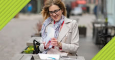 Smiling woman sitting at outdoor table with smartphone and tablet