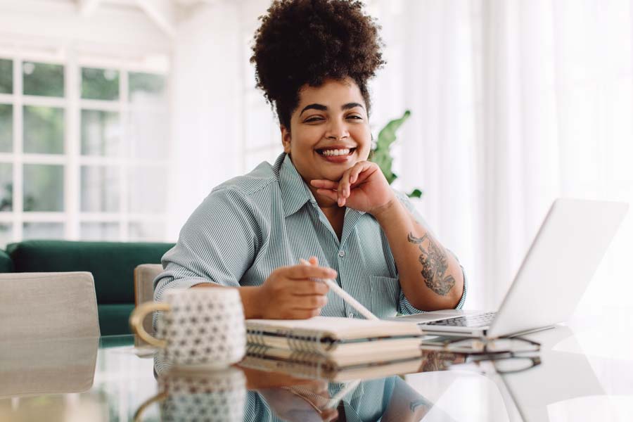 Woman smiling while working on laptop at home