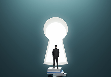A man standing on a stack of books in front of a large door in the shape of a key hole