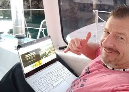 Keith working on his laptop while in his sailboat