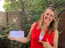 Mindy McHorse pointing to a check that she is holding