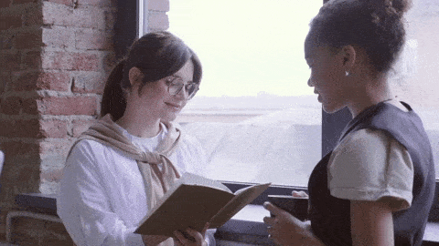 A woman writing notes while talking with another woman